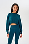 A woman wearing a SPLITS59 Noah Fleece Crop Sweatshirt in Peacock and leggings.