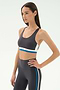 Woman wearing the SPLITS59 Maci Airweight Bra in Graphite/White with matching high-waisted leggings, posing with one hand on her hip—ideal activewear for gym workouts.