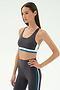 Woman wearing the SPLITS59 Maci Airweight Bra in Graphite/White with matching high-waisted leggings, posing with one hand on her hip—ideal activewear for gym workouts.
