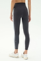 A person wears SPLITS59 Ella High Waist Airweight 7/8 leggings in Graphite/Stone Blue with white athletic shoes, standing against a plain light background—ideal for hot yoga sessions.