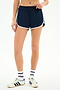 A person wears the SPLITS59 Megan Woven Nylon Run Short in Indigo/Creme, paired with white tube socks featuring red and blue stripes, and white sneakers with navy stripes, standing against a plain white background.