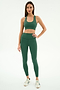 A woman faces forward wearing the SPLITS59 Sara Airweight Bra in Arugula with matching high-waisted leggings and white sneakers, set against a plain white background.