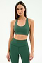 A woman wears the SPLITS59 Sara Airweight Bra in Arugula with matching high-waisted leggings, both crafted from nylon and spandex, standing against a plain light background.
