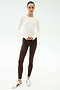 A woman stands against a white background wearing the SPLITS59 Airweight Lite Long Sleeve Waist Length tee in white—quick-drying, lightweight, and ideal for gym workouts or casual days.