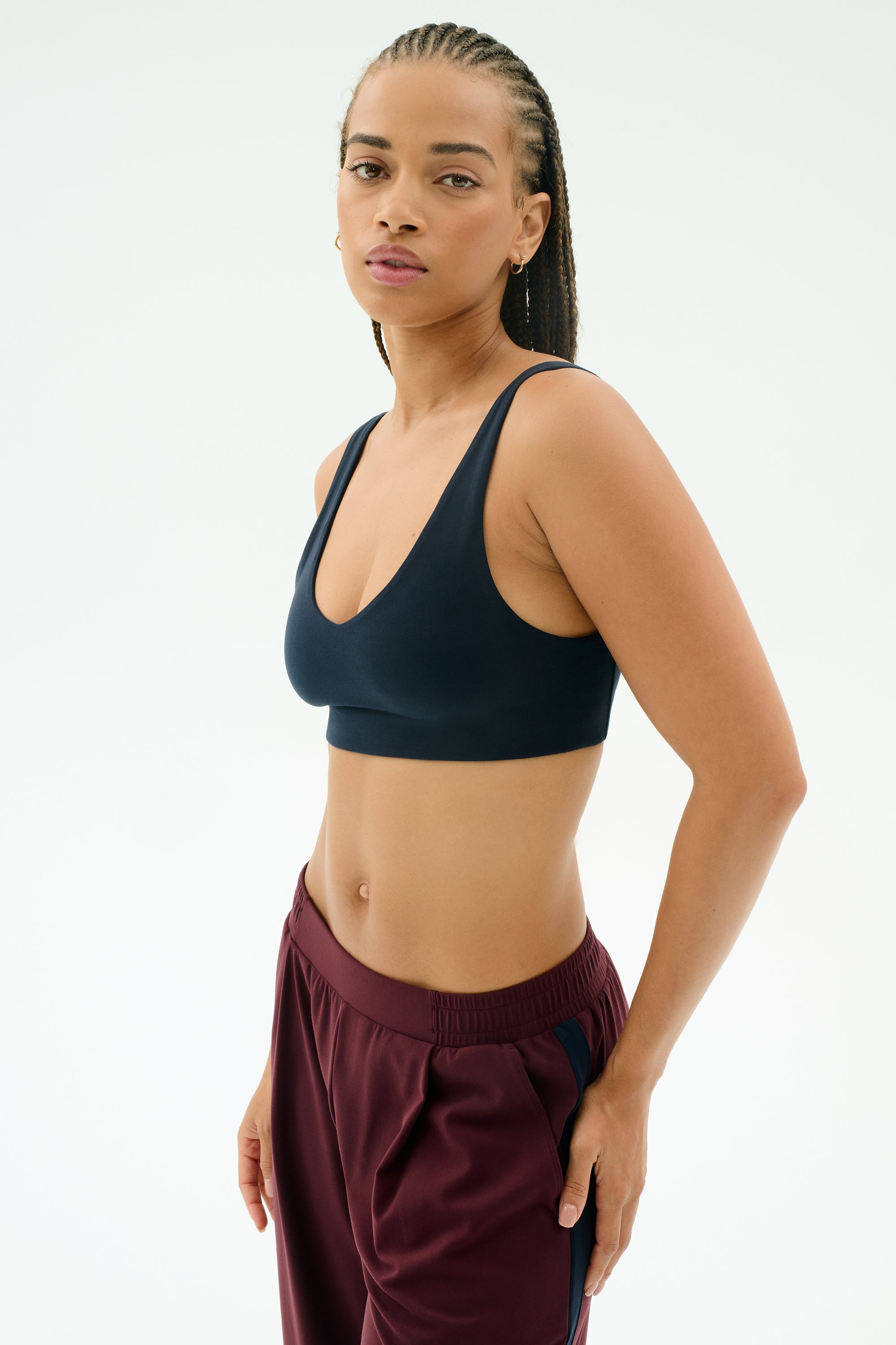 A woman wears the SPLITS59 Airweight Scoop Back Bra in Indigo, standing against a plain light background and looking at the camera.