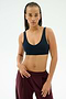 A woman with braided hair wears the SPLITS59 Airweight Scoop Back Bra in Indigo, standing against a plain light background.