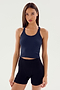 A woman stands against a plain background, facing forward with arms relaxed at her sides, wearing the SPLITS59 Ashby Rib Crop tank top and black shorts.