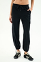 A person wears SPLITS59 Nico Airweight Cargo Pant in black for lightweight comfort, paired with black athletic shoes, standing against a plain light background.