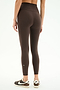 Someone stands with their back to the camera in SPLITS59’s Airweight High Waist Legging - Dark Chocolate and black Nike sneakers against a white background—ideal for hot yoga sessions.