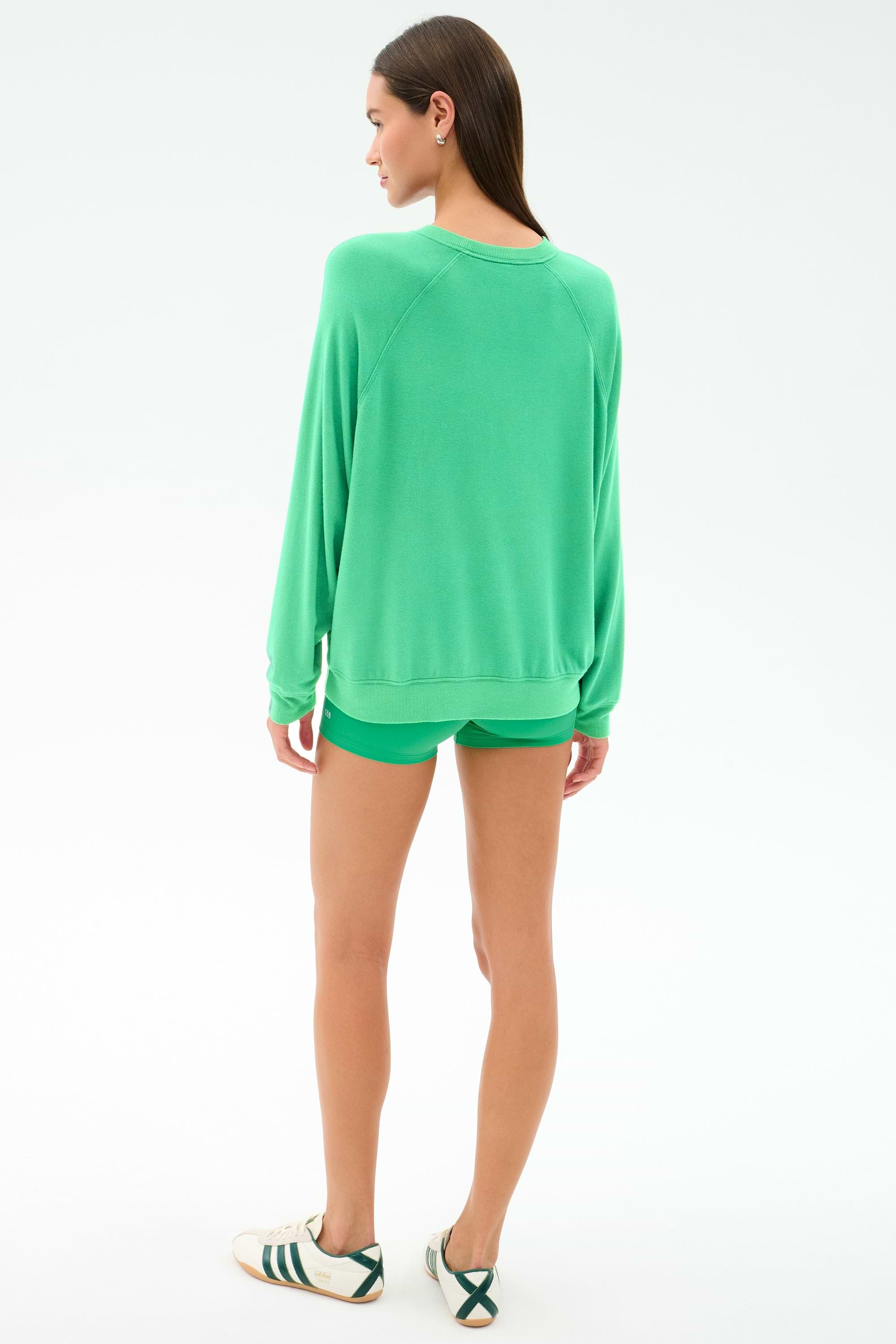 A woman faces away, wearing the SPLITS59 Andie Oversized Fleece Sweatshirt in Spearmint with matching shorts and white sneakers with black stripes, set against a plain white background.