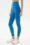 A person stands on a plain white background wearing SPLITS59 Airweight Super High Waist 7/8 leggings in Stone Blue and white athletic shoes, ideal for hot yoga.