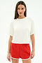 A person faces forward against a white background, wearing the SPLITS59 Djuna Oversized Jersey Tee in white and red athletic shorts with white trim.