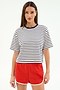 A woman stands facing forward, wearing the SPLITS59 Djuna Oversized Jersey Tee in White/Indigo Stripe with bright red athletic shorts.