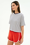 A woman wears the SPLITS59 Djuna Oversized Jersey Tee in White/Indigo Stripe with red athletic shorts, standing against a plain white background.