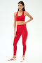 A woman poses against a plain background in SPLITS59's Airweight High Waist Legging in Pirate Red with a matching sports bra and white sneakers with red stripes—ideal attire for hot yoga.