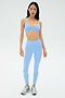 A woman faces forward wearing the SPLITS59 Theo Rigor Bra in Skylight with matching leggings and silver athletic shoes, set against a plain light background.