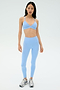 A woman faces forward wearing the SPLITS59 Theo Rigor Bra in Skylight with matching leggings and silver athletic shoes, set against a plain light background.