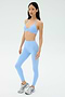A person wears the SPLITS59 Theo Rigor Bra in Skylight, styled with matching high-waisted leggings and white athletic shoes against a plain light background.