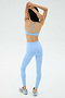 A woman wearing the SPLITS59 Theo Rigor Bra in Skylight and leggings stands with her back to the camera, arms raised overhead, and running shoes on.