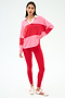 A woman stands against a white background wearing the SPLITS59 Katie Fleece Rugby in Strawberry/Pirate Red.