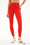 A person wearing SPLITS59 Airweight Rib High Waist 7/8 leggings in Lotus Red with red and white sneakers stands against a plain white background.