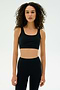 A woman with curly hair wears the SPLITS59 Airweight Rib Bra in black, paired with matching high-waisted leggings, against a plain light background.