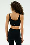 A person with curly hair faces away against a plain light background, wearing the SPLITS59 Airweight Rib Bra in black and matching leggings.