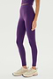Person standing in SPLITS59 Airweight High Waist Legging in Black Currant, made of an 81% nylon and spandex blend, and beige sneakers on a white background. Photo cropped to show torso to feet.