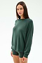 A woman with straight brown hair wears the SPLITS59 Andie Fleece Sweatshirt in Military, styled with matching fitted shorts, standing against a plain white background.