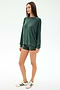 A woman stands against a plain white background wearing the SPLITS59 Andie Fleece Sweatshirt in Military, matching green shorts, and white sneakers with green stripes.