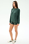 A woman stands against a plain white background wearing the SPLITS59 Andie Fleece Sweatshirt in Military, matching green shorts, and white sneakers with green stripes.