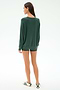A woman stands facing away in a SPLITS59 Andie Fleece Sweatshirt - Military, matching green shorts, and white sneakers with green stripes against a plain white background.