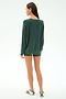 A woman stands facing away in a SPLITS59 Andie Fleece Sweatshirt - Military, matching green shorts, and white sneakers with green stripes against a plain white background.