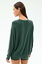A person with long brown hair stands facing away from the camera, wearing the SPLITS59 Andie Fleece Sweatshirt in Military, a dark green pullover made in Los Angeles.