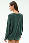 A person with long brown hair stands facing away from the camera, wearing the SPLITS59 Andie Fleece Sweatshirt in Military, a dark green pullover made in Los Angeles.