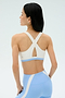 A woman with long black hair models the SPLITS59 Miles Rigor Bra in Skylight/White, featuring a crisscross back, paired with light blue leggings against a plain light background.
