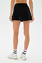 Model wears the SPLITS59 Venus High Waist Rigor Skort in black, paired with white socks featuring black stripes and white sneakers, shown from the back against a plain white background.