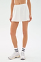 A person wears the SPLITS59 Venus High Waist Rigor Skort in white, paired with white sneakers and white socks with black text, standing against a plain white background.