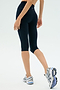 A person is photographed from behind against a plain background wearing SPLITS59 Airweight High Waist 16" Legging in indigo and white athletic shoes.