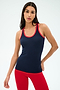 A woman in the SPLITS59 Ashby Rib Tank - Indigo/Pirate Red stands against a plain light background, wearing red leggings and ready for yoga or gym workouts.