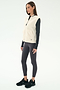 A woman wears the SPLITS59 Aster Sherpa Vest - Creme over a black long-sleeve shirt, dark leggings, and black sneakers—an ideal cool weather workout look—against a plain white background.