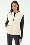 A woman stands against a plain light background wearing the SPLITS59 Aster Sherpa Vest - Creme over a black long-sleeve top and leggings—an ideal warm layer for cool weather workouts.