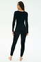 A person with braided hair, barefoot, wears the SPLITS59 Chloe Airweight Jumpsuit in black and stands facing away against a plain white background.