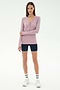 A woman stands against a plain background wearing the SPLITS59 Louise Rib Henley in blush, black biker shorts, white crew socks, and white sneakers.