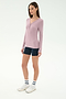 A woman stands against a plain white background wearing the SPLITS59 Louise Rib Henley in Blush, navy bike shorts, white sneakers, and white crew socks.