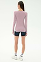A woman stands facing away, wearing the SPLITS59 Louise Rib Henley in blush, navy blue shorts, white striped socks, and white sneakers against a plain white background.