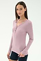 A woman with straight brown hair wears the SPLITS59 Louise Rib Henley in blush and black shorts, standing against a plain white background.