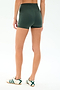 A person wearing SPLITS59 Airweight High Waist 3.5” Short - Military and white sneakers with green stripes, standing on a white background, shown from the back.