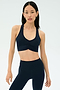 A woman wearing the SPLITS59 Airweight Bra with Ruching in Indigo stands against a plain light background.