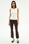 A woman faces forward against a white background, wearing the SPLITS59 Carter Airweight Lite Tank in white, paired with brown flared spandex pants with side stripes and brown sneakers.